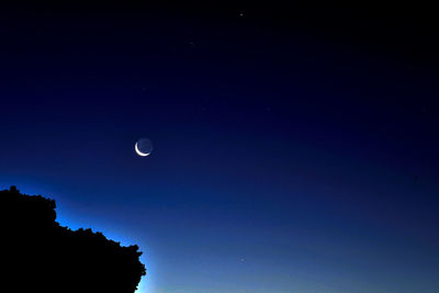 Low angle view of moon against clear blue sky