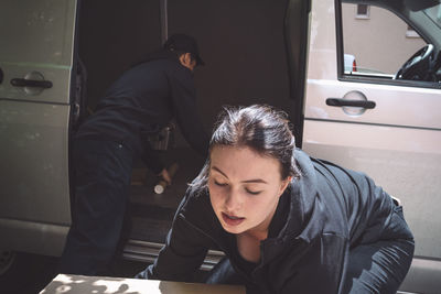 Male and female delivery workers arranging package outside truck