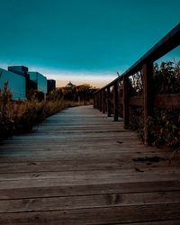 Empty footpath amidst trees against clear blue sky