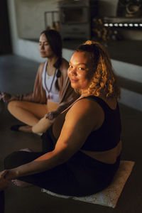 Portrait of smiling plus size woman sitting with female friend at retreat center