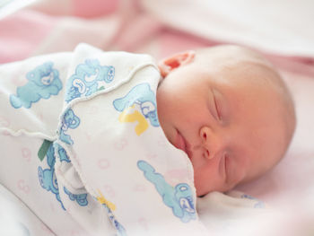 Close-up of baby sleeping in bed