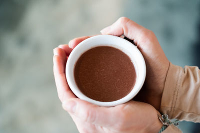 Female hand holding a cup of pure shamanistic ceremonial cacao drink.