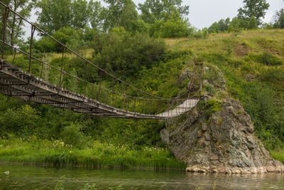 Old wooden suspension bridge over a small river
