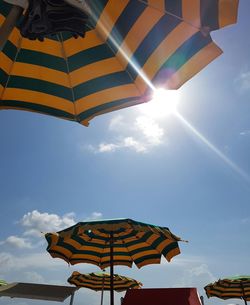 Low angle view of sunshades against sky