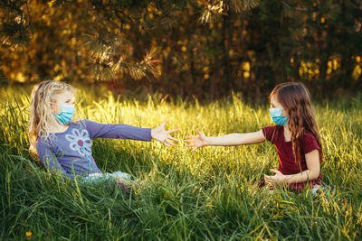 Friends wearing masks while sitting on grass