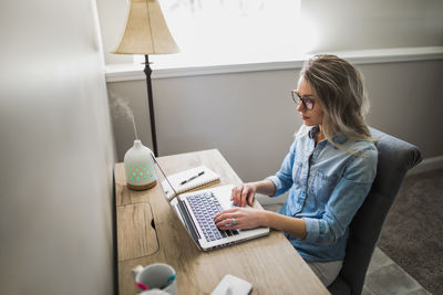 Woman using phone while sitting on table