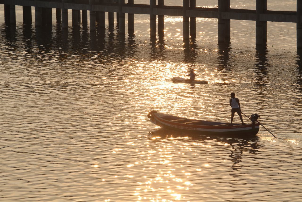 SILHOUETTE MAN ON BOAT IN LAKE AGAINST SKY