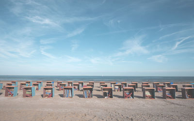 Hooded chairs on beach against sky