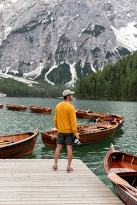 Rear view of man standing on lake against mountain