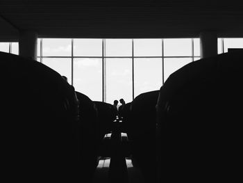 Silhouette people against glass window in building