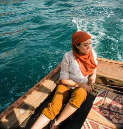 High angle view of young woman sitting on pier over sea