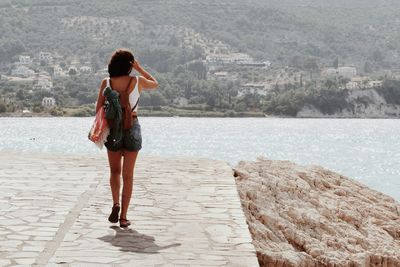 Rear view of woman walking on footpath by sea