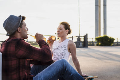 Young couple drinking beer from bottles at sunset