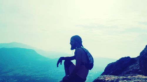 Side view of man standing on mountain against sky