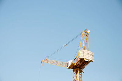 Low angle view of crane against clear blue sky