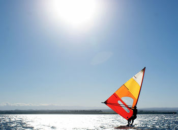 Person on sea against clear sky during sunny day