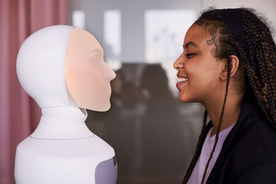 Young woman looking at robot voice assistant