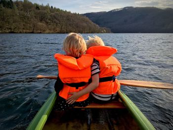 Rear view of woman sitting on boat against lake