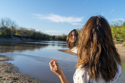 Portrait of woman by lake against sky