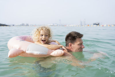 Happy girl with father swimming in sea