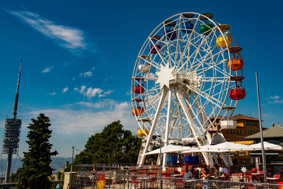 Low angle view of ferris wheel against blue sky