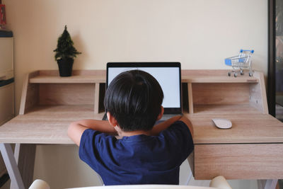 Rear view of man sitting on table at home