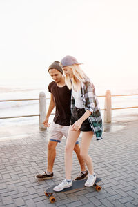 Full length of young woman standing on footpath