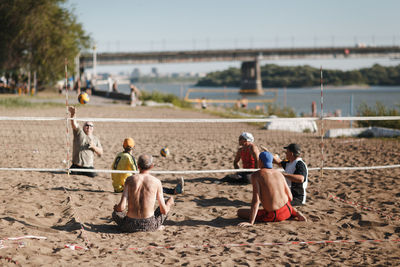 Rear view of people sitting on beach