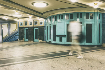 Blurred motion of man walking in illuminated modern building