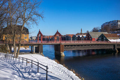 Built structure by river against clear blue sky