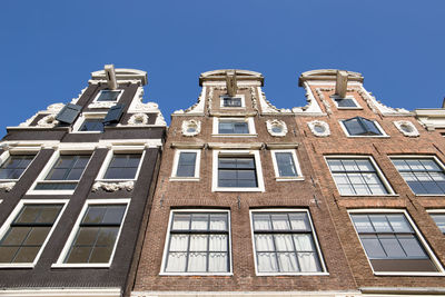 Low angle view of canal houses in amsterdam against clear blue sky