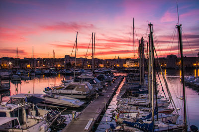 Sailboats moored at harbor against sky during sunset