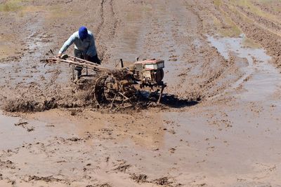 Man with agricultural machinery working on wet farm