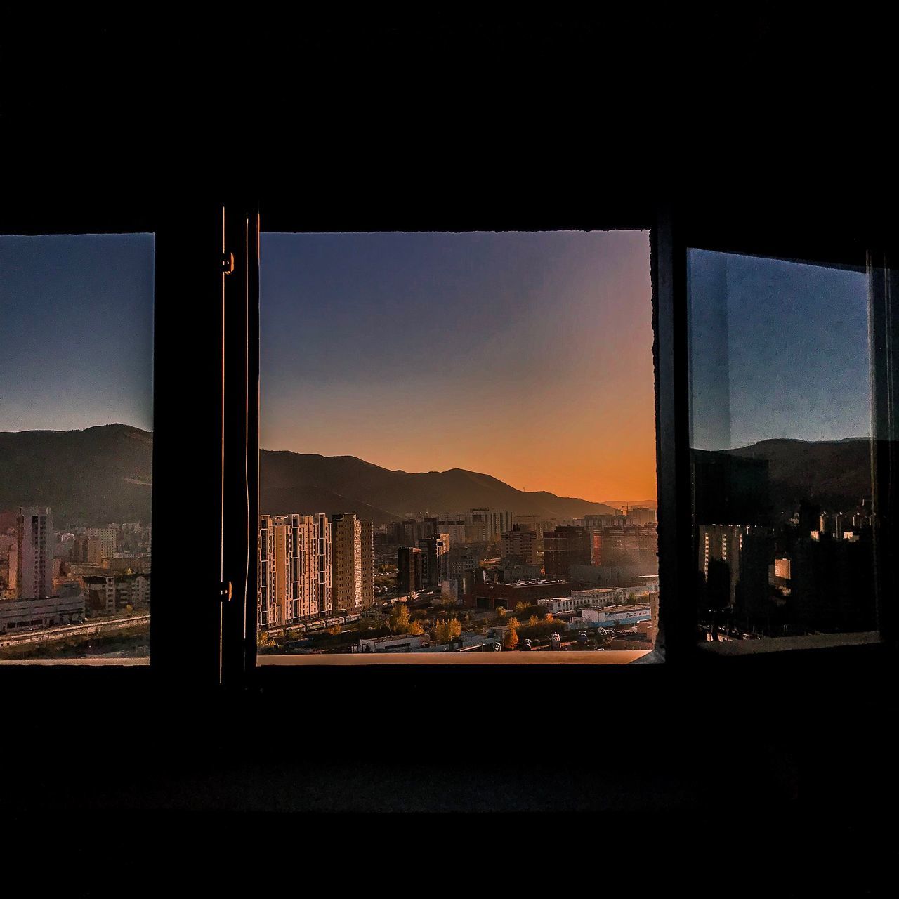 window, sky, glass - material, architecture, sunset, mountain, transparent, city, built structure, nature, indoors, no people, building, cityscape, sunlight, mountain range, orange color, landscape, glass