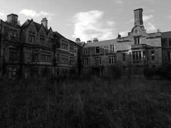 Building by grassy field against sky