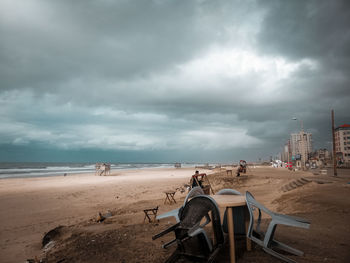 People on beach against cloudy sky