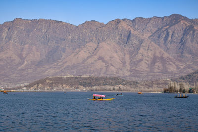 Boats in lake against mountains