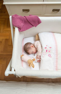 High angle view of cute girl lying on sofa