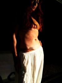 Close-up of girl standing against black background