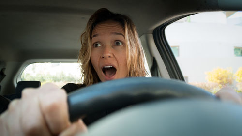Headshot of shocked woman driving car