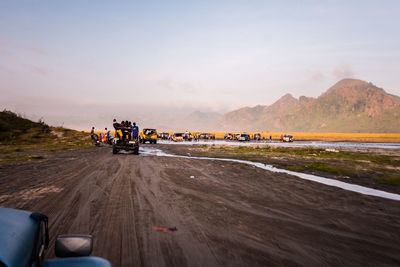 Cars on riverbank against sky