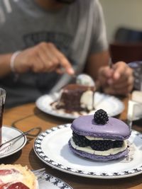 Midsection of man eating dessert while sitting at table in restaurant