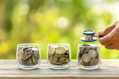 Close-up of hand holding coins on table