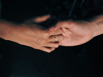 Close-up of couple holding hands in dark