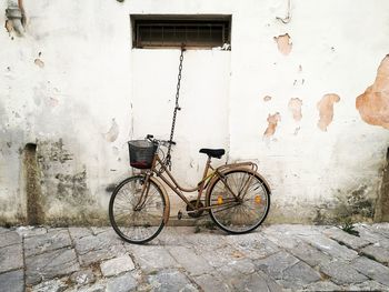 Bicycle parked against brick wall