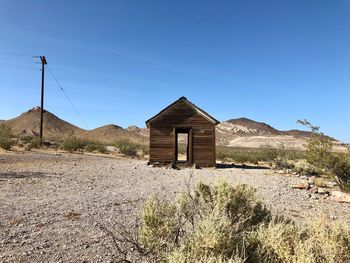 Abbandoned house on field against clear blue sky