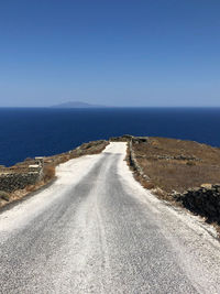 Empty road by sea against clear sky