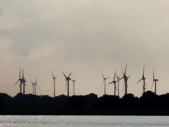 Silhouette wind turbine against sky during sunset