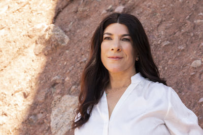 Portrait of young woman standing against rock