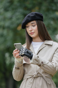 Beautiful woman with prosthetic hand using mobile phone